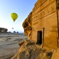 Hot air balloons flying in the distance near one of the tombs in